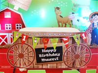 Cake table setup like a push cart with a bunting and text mentioning the baby name